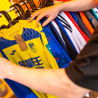 Shopper browsing vintage football shirts at the market